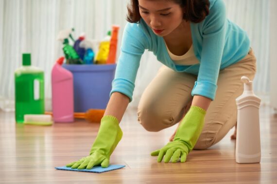 Young Asian housewife cleaning stain on wooden floor